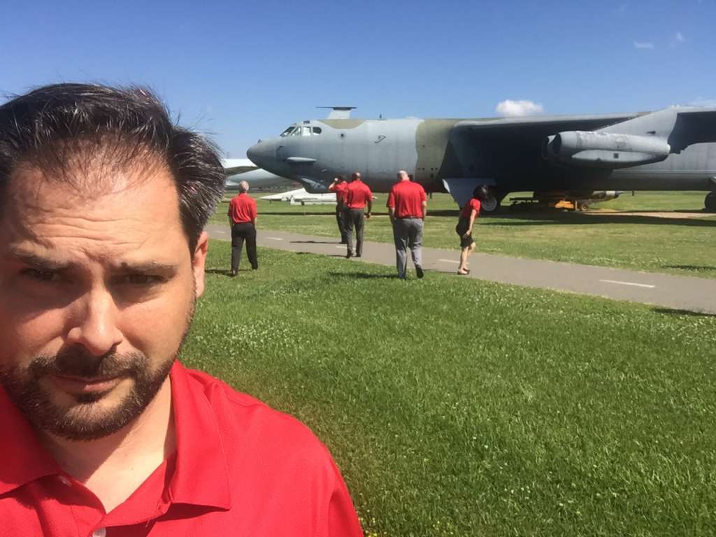 Mike Garcia with green grass and military planes behind him.